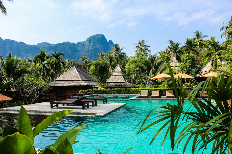 Resort pool framed by palms and limestone hills in Thailand